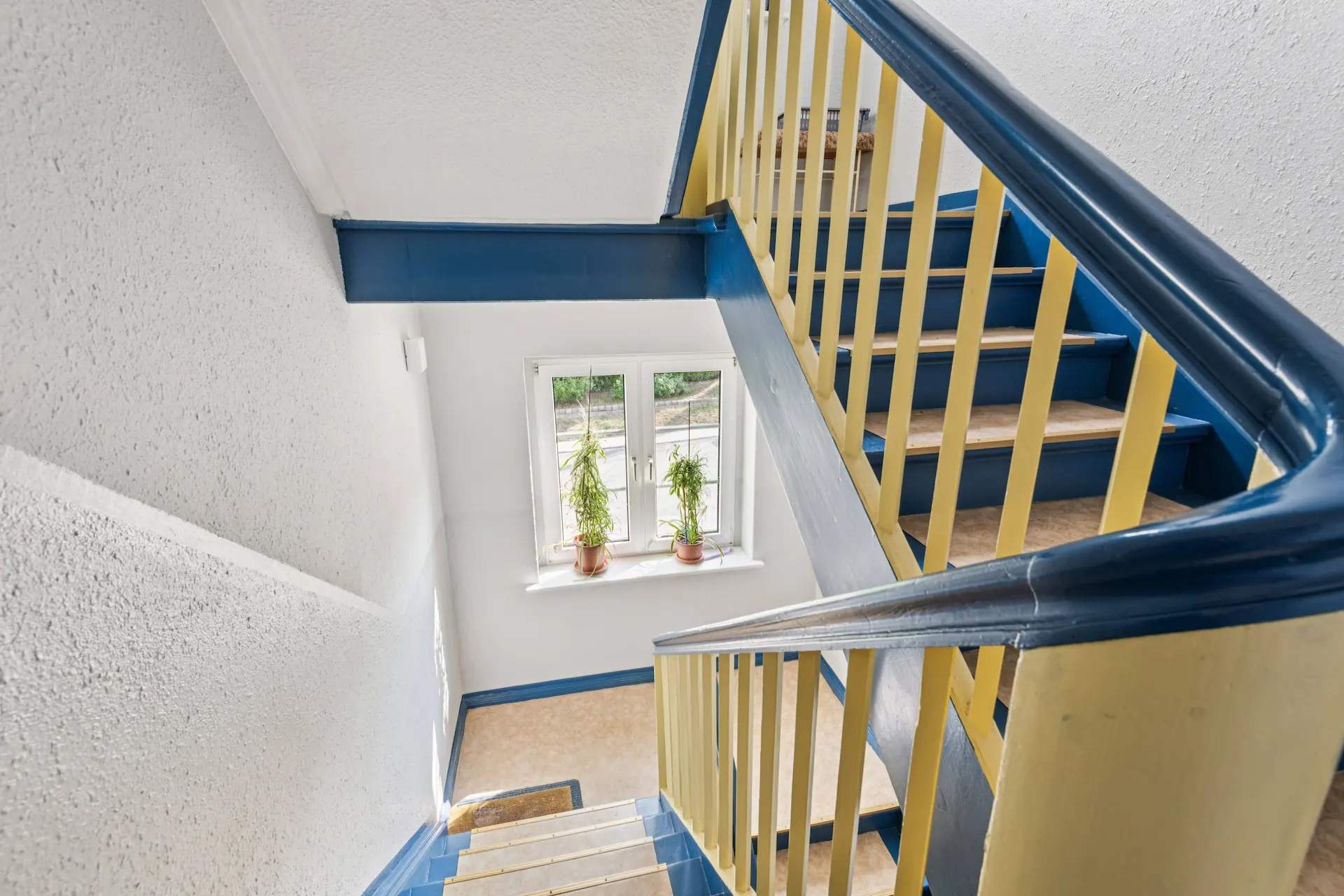 Treppenhaus eines Mehrfamilienhauses in Leipzig mit gelben und blauen Treppengeländer